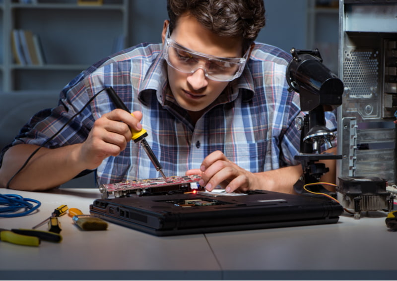 Technician soldering electrical parts on motherboard