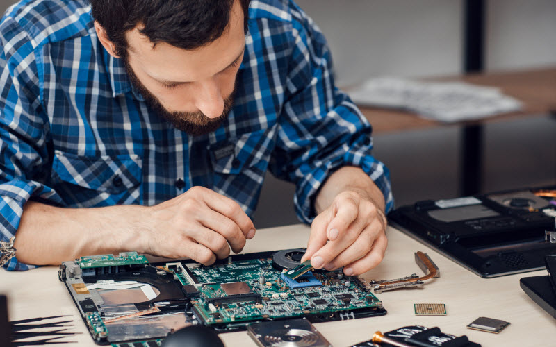 Repairman disassembling laptop motherboard