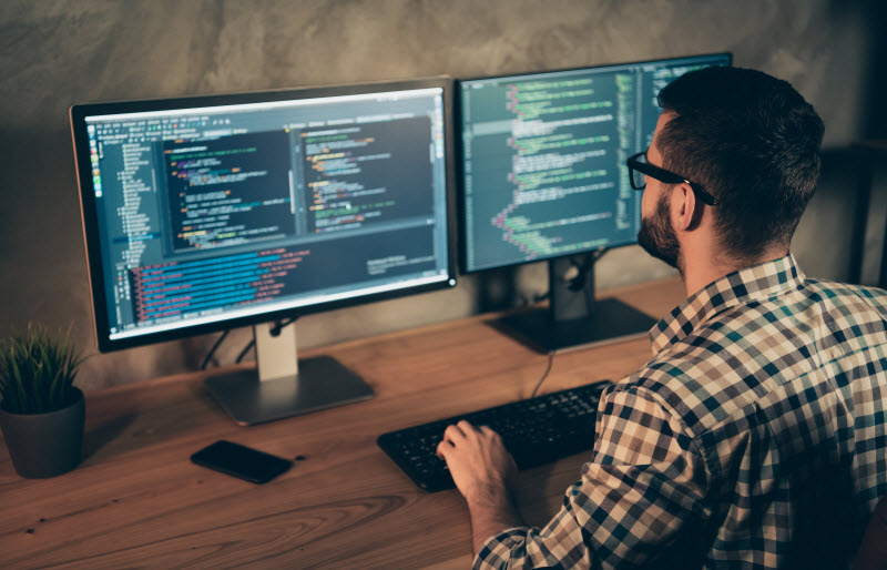 Developer coding in a double screen desktop
